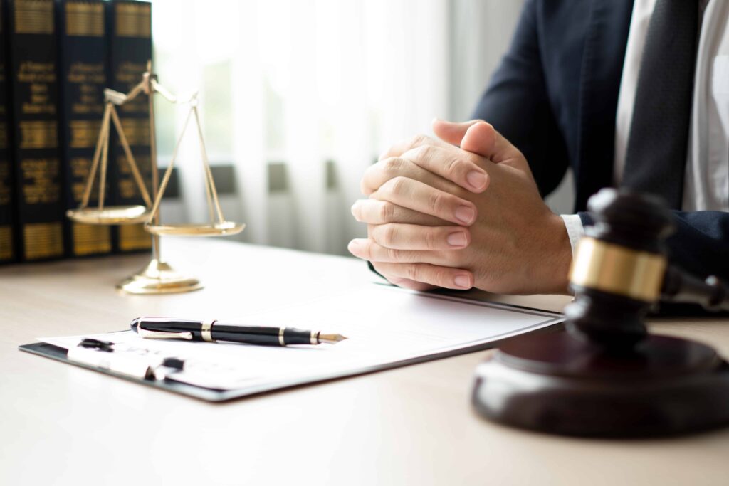 Lawyer sitting at desk with legal documents, gavel, and scales of justice in office