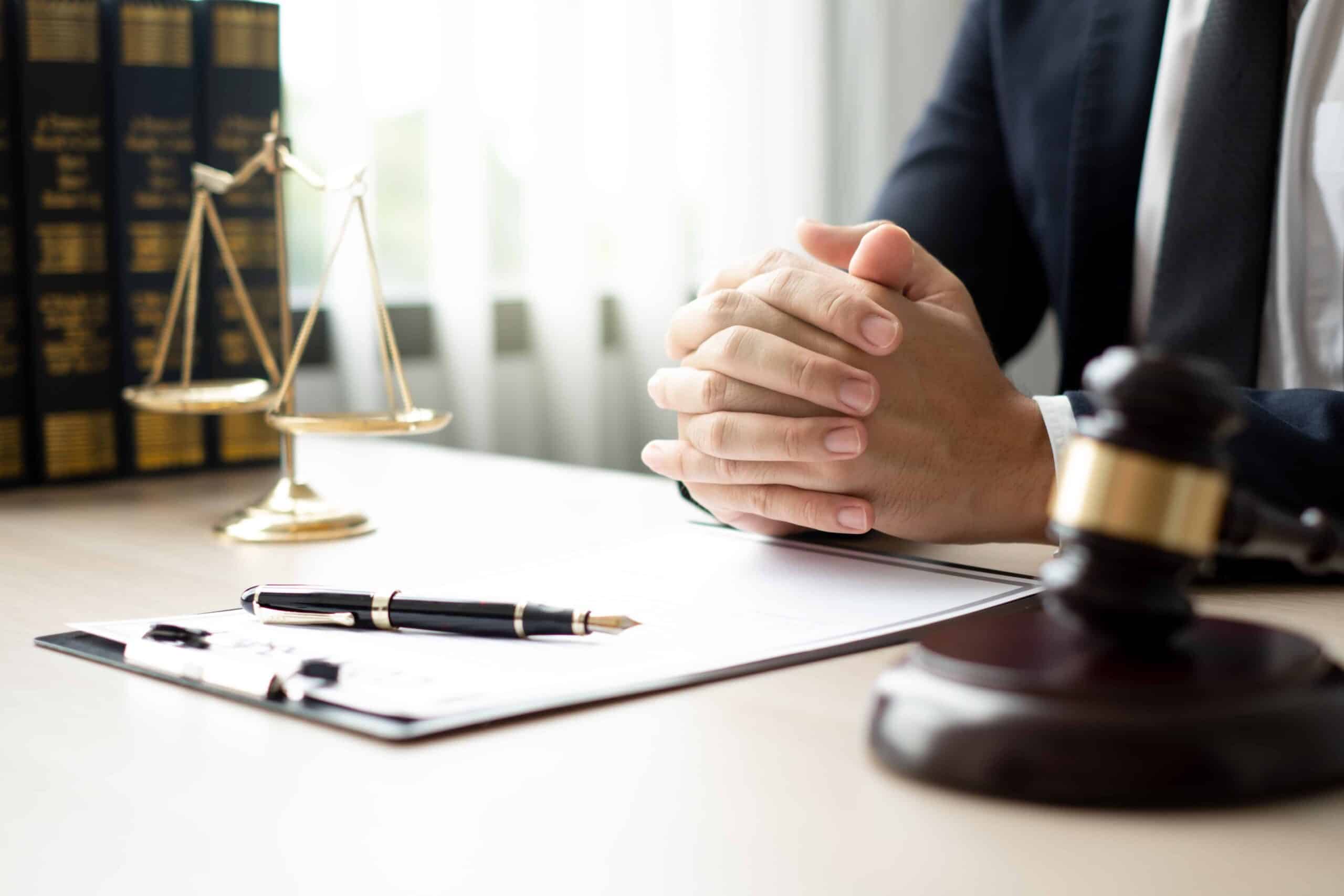 Lawyer sitting at desk with legal documents, gavel, and scales of justice in office