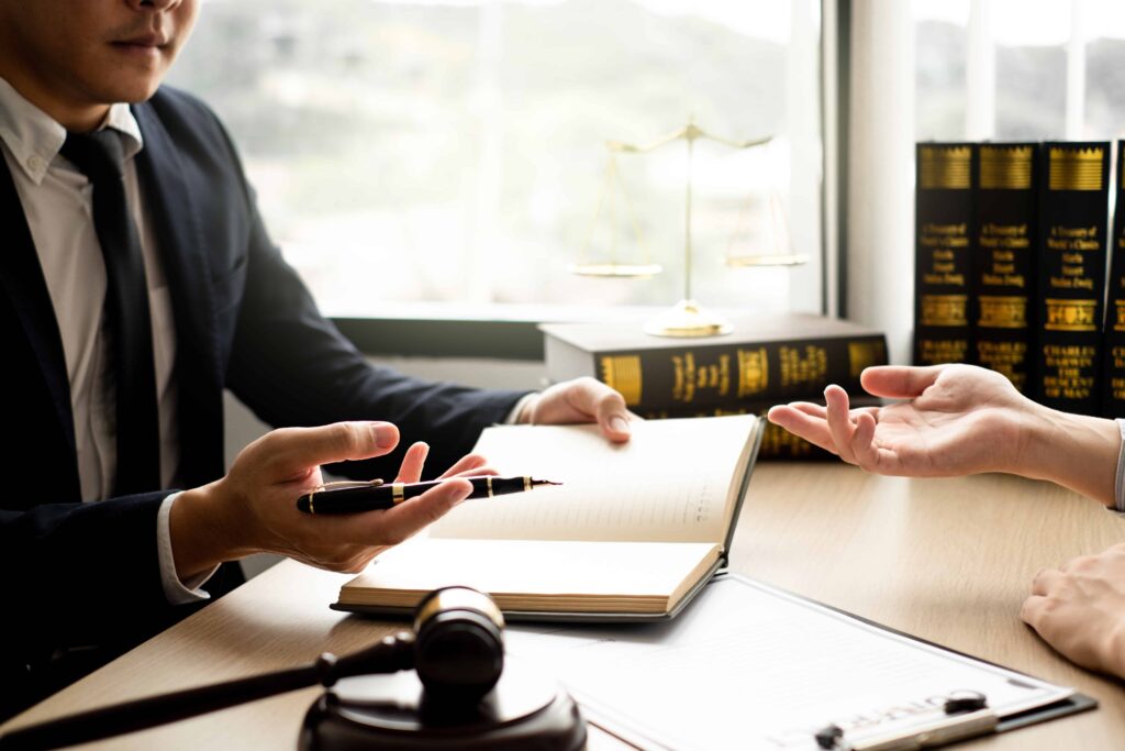 Lawyer consulting with client in office with legal books, gavel, and scales of justice