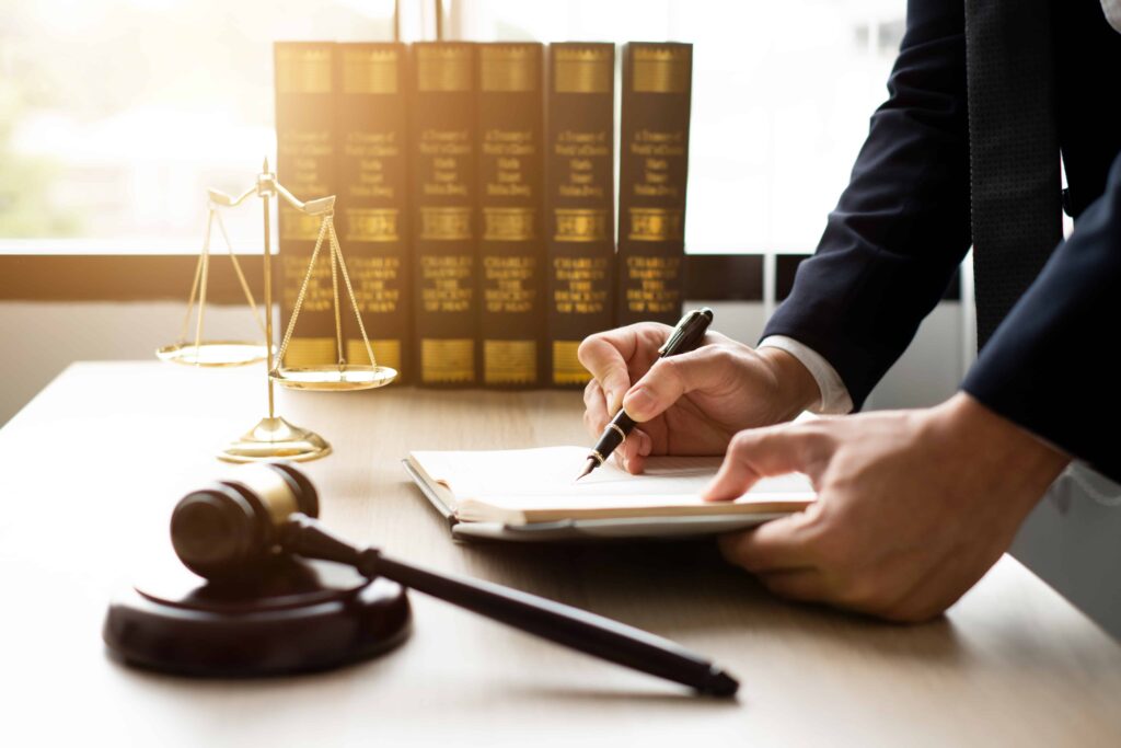 Lawyer writing legal notes with gavel, scales of justice, and law books in office