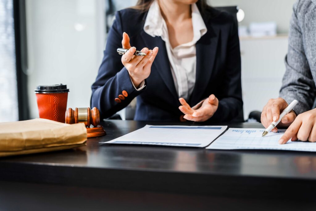 Lawyer consulting client with legal documents and gavel on desk during case review